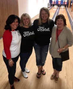 4 women pose together at a bowling alley